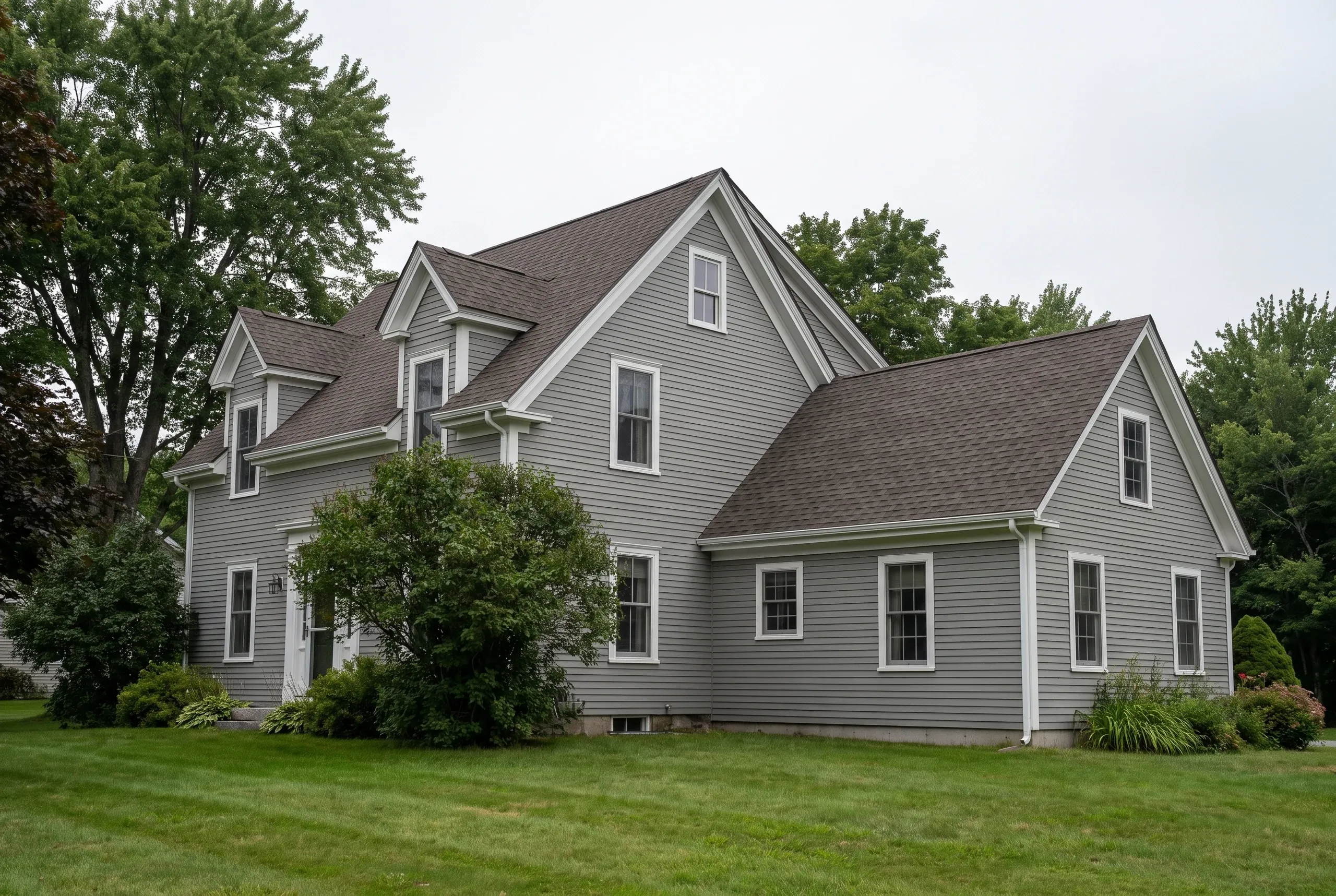Roofing contractor Bucksport Maine: gray clapboard cape with brown asphalt shingle roof, front dormers and side ell