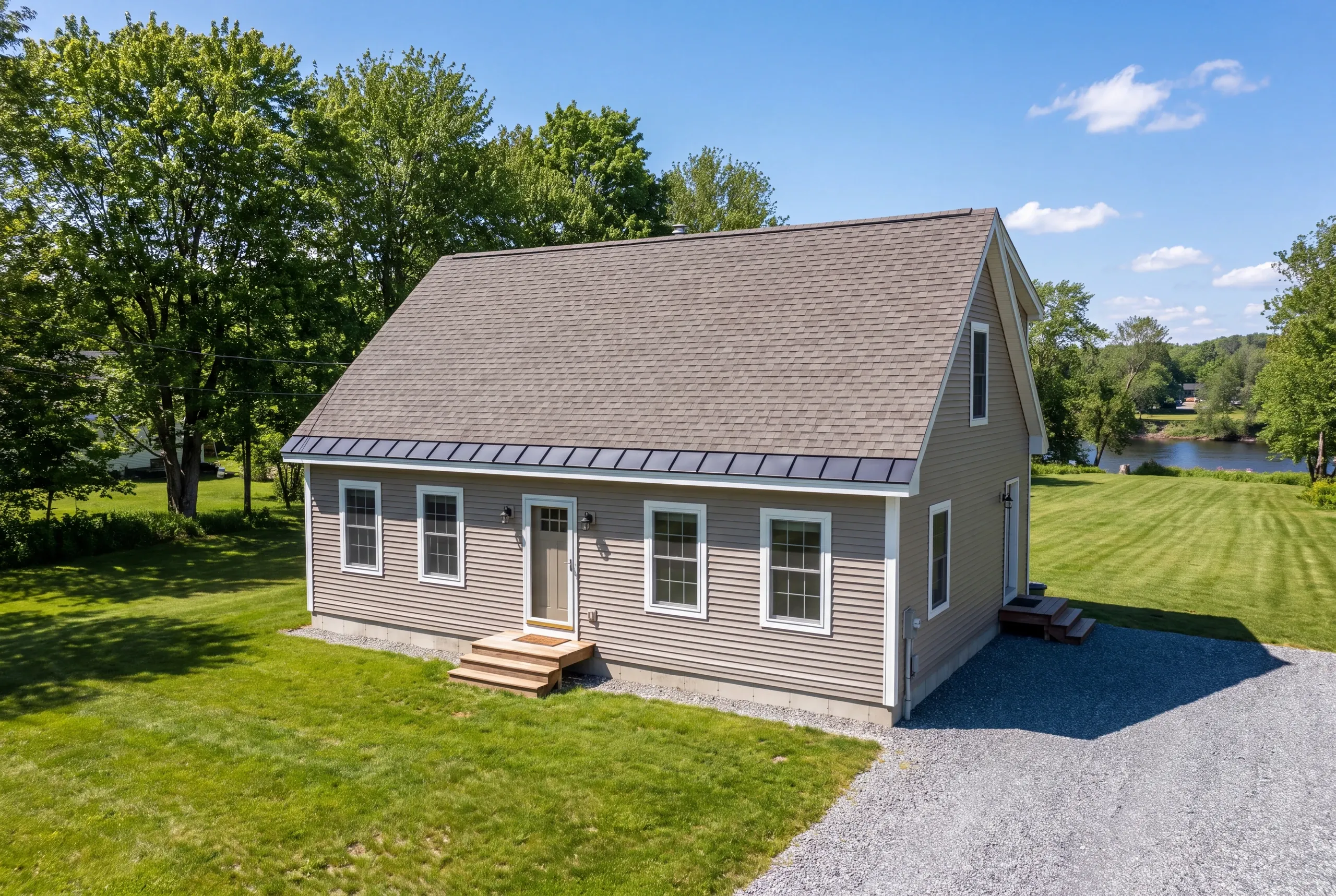 Roof replacement contractor Fairfield Maine: aerial view of a tan-sided cape with gray shingles and a dark metal eave band