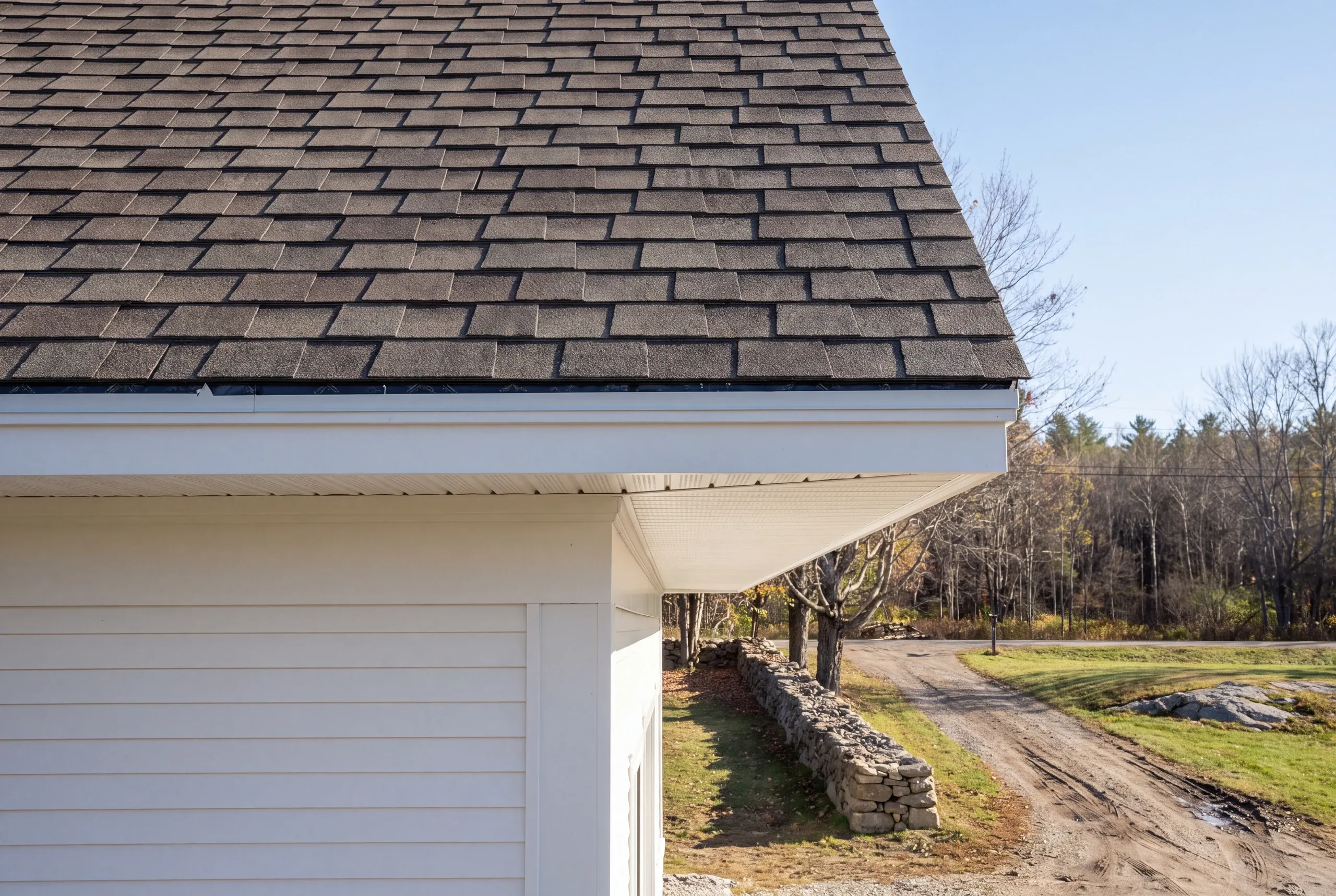 Residential roofing contractor Searsmont Maine: eave corner with brown architectural shingles, white fascia and open vented soffit panels