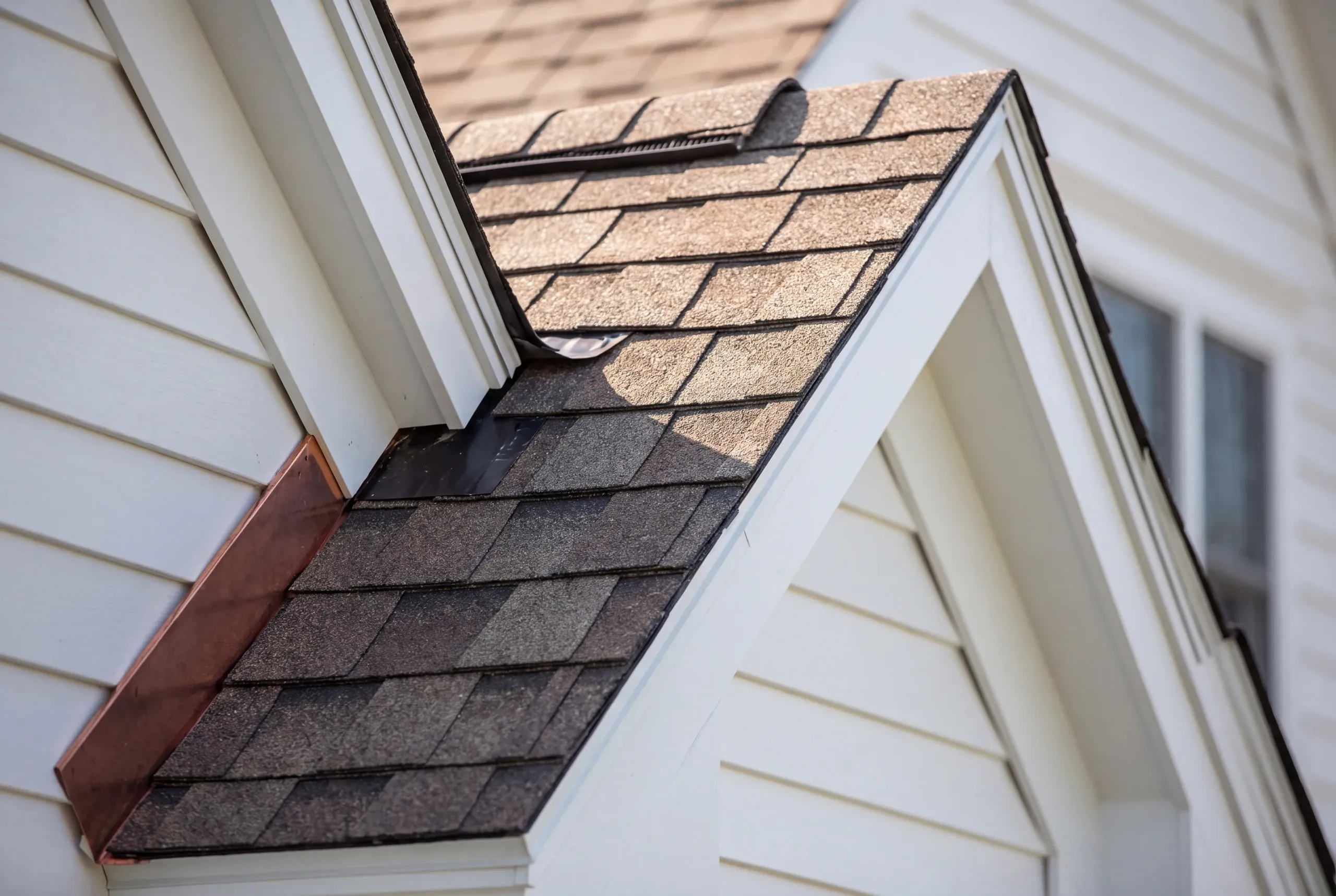 Residential roofing contractor Windsor Maine: small gable roof with brown arch shingles, copper sidewall flashing and white lap siding