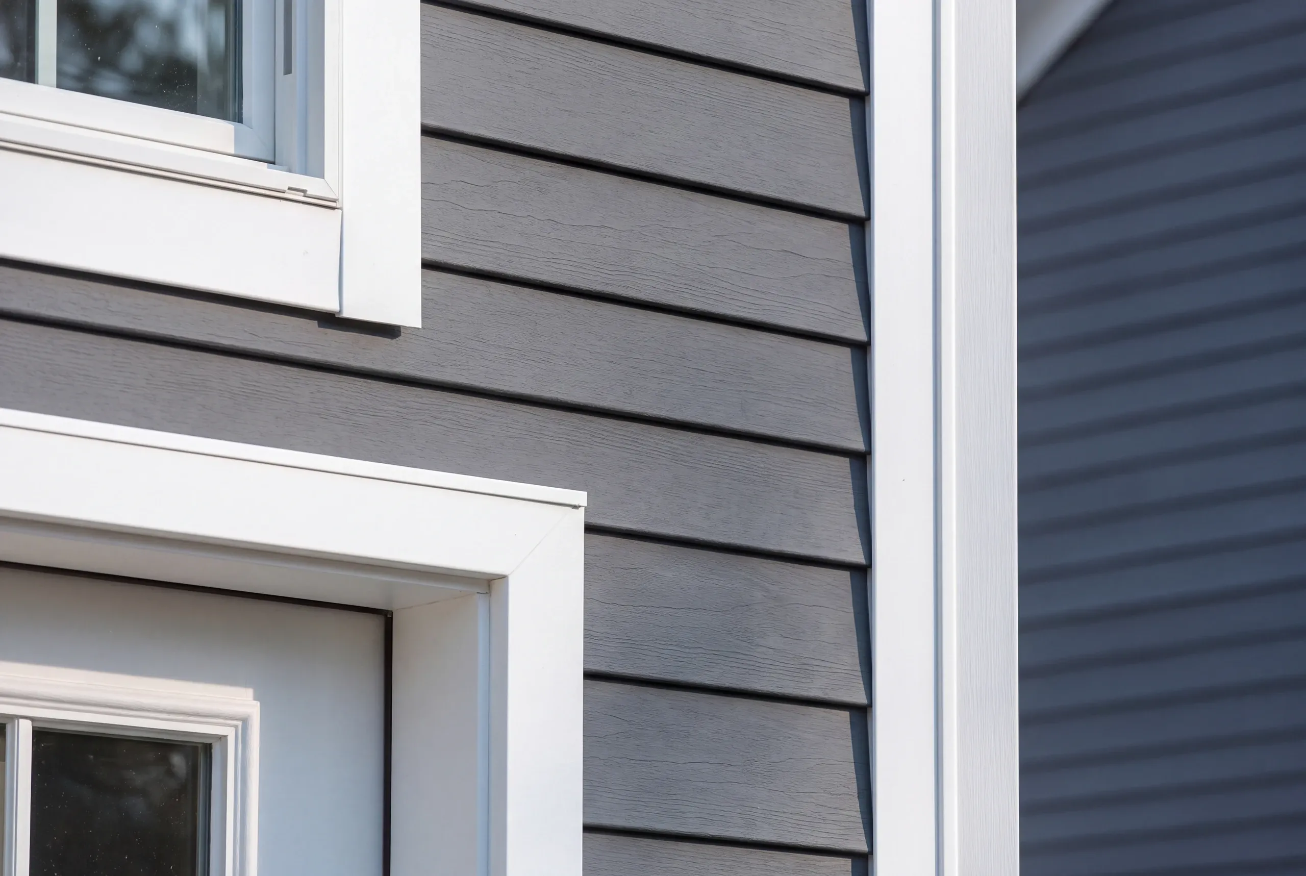 Siding installer Gardiner Maine: tight view of gray wood-grain lap siding with white window and door casings