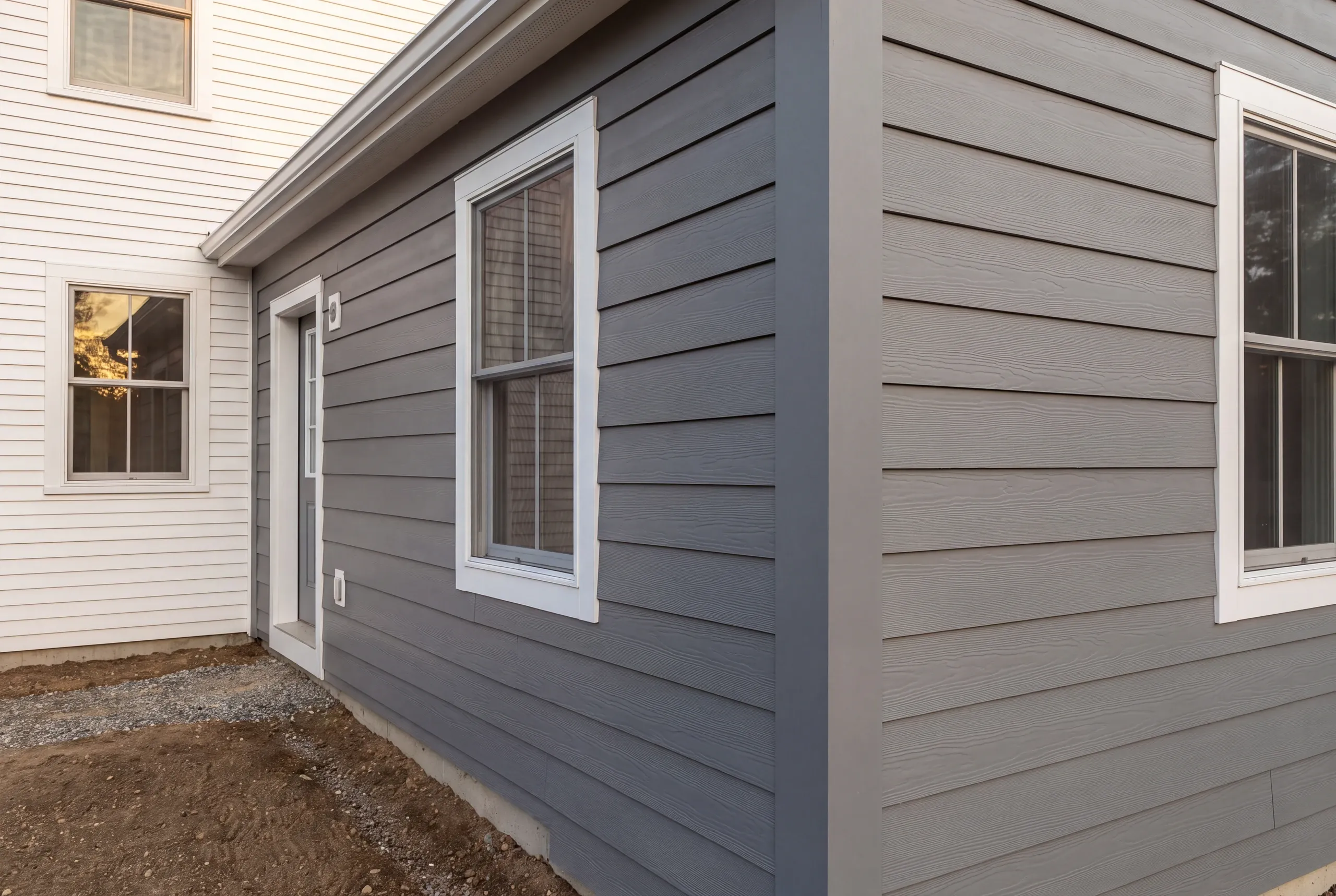 Siding installer Warren Maine: inside corner where white lap siding on the main house meets gray wood-grain lap siding
