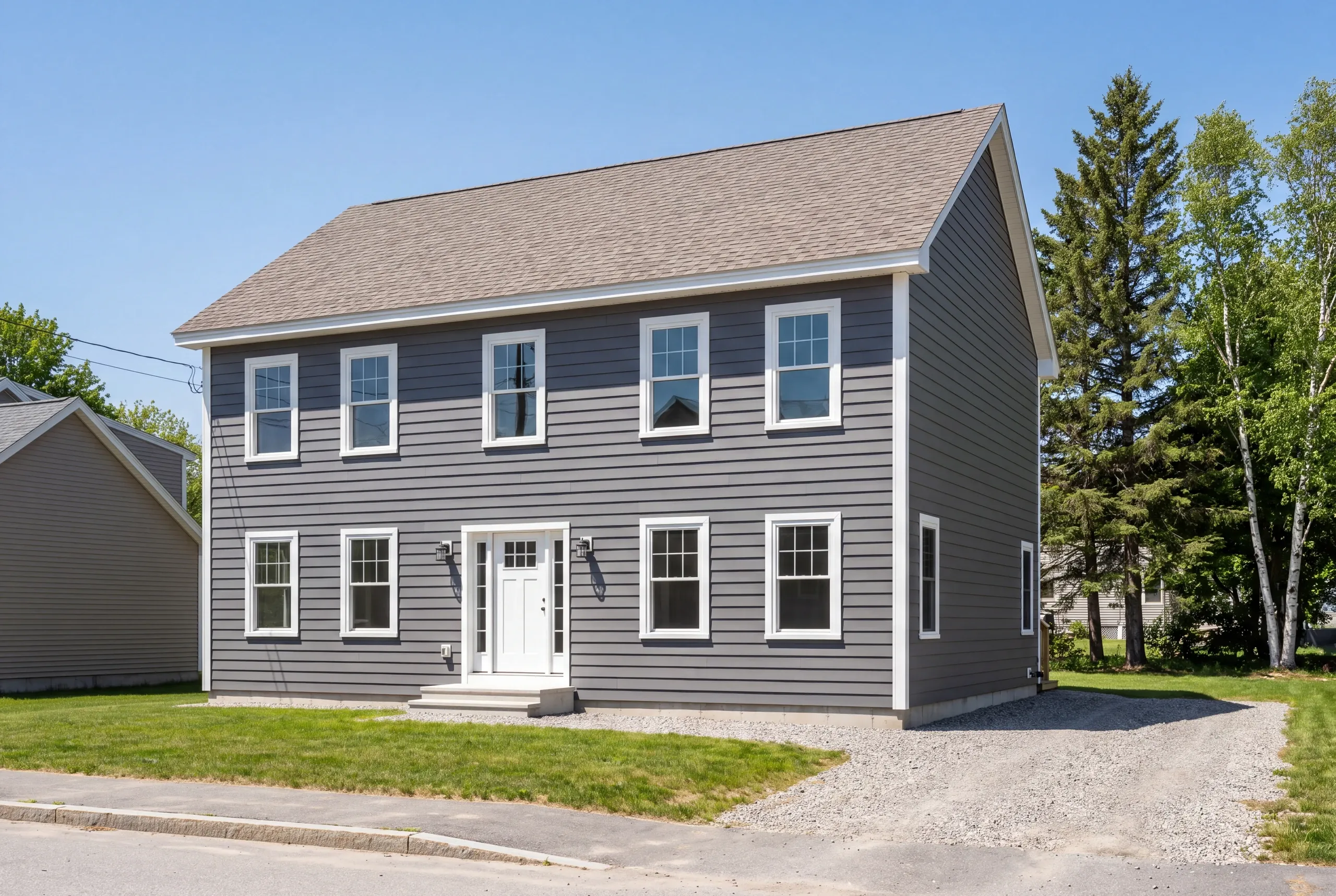 Exterior siding contractor Waterville Maine: two-story gray lap-sided colonial with a tan shingle roof facing a sidewalk and street